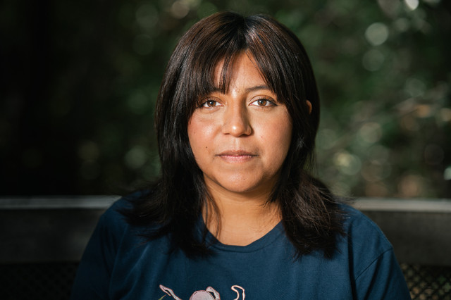 Head and shoulders portrait of Melanie Alejo, against a leafy green background
