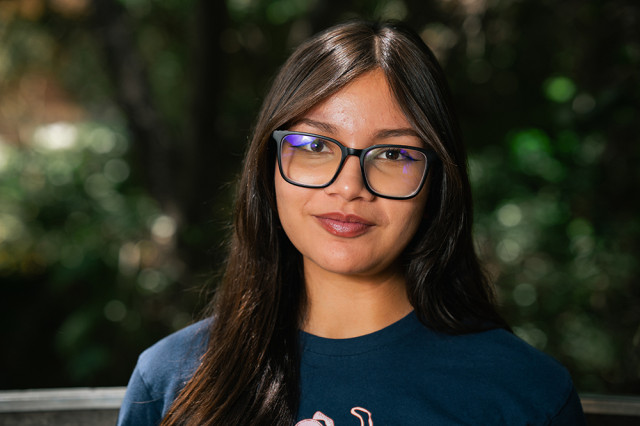 Head and shoulders portrait of Mia Contreras, against a leafy green background