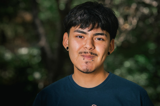 Head and shoulders portrait of Nathan Prado, against a leafy green background
