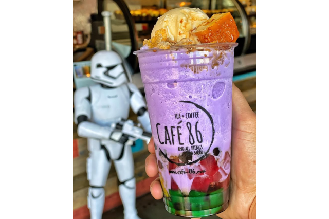Colorful, purple, red, and green boba drink in large plastic cup, topped with yellow ice cream, with a toy stormtrooper in the background.