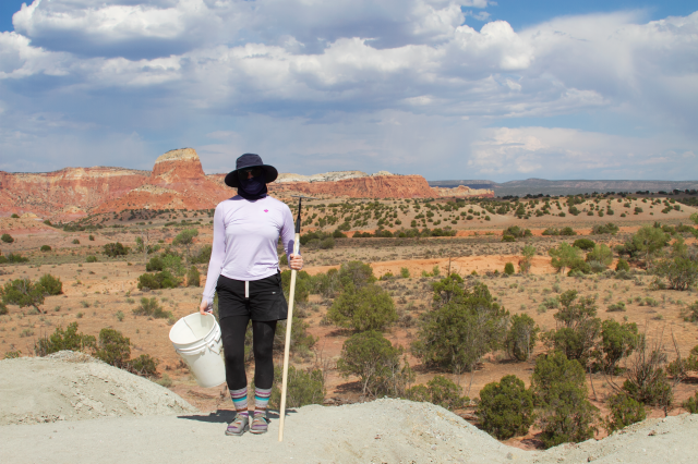 Woman holds shovel and bucket while completely covered