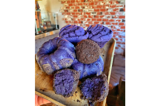 Plate stacked with purple, ube-flavored muffins, cookies, and mini-cakes.