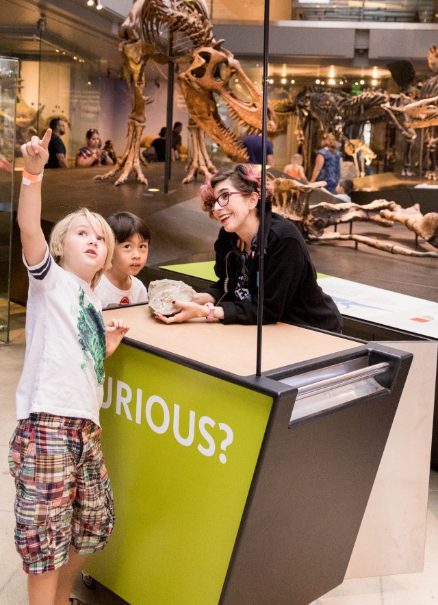 gallery interpreter at curiosity cart talking to a child in Dinosaur Hall