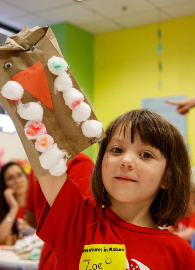 Little girl holding up bird craft.