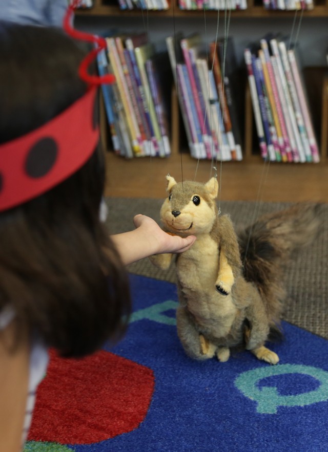 A young child interacts with a squirrel puppet at a Nature Day event.