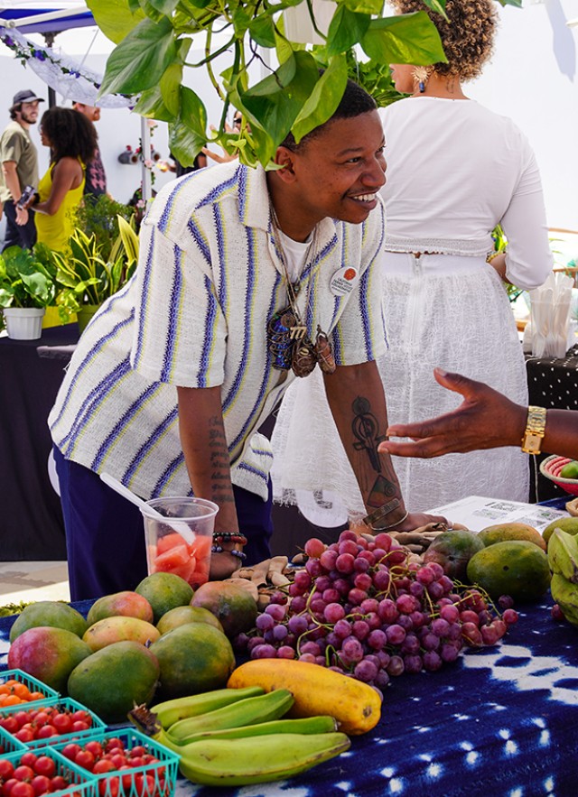 Customer talking with a farmers market across a table with colorful produce on display