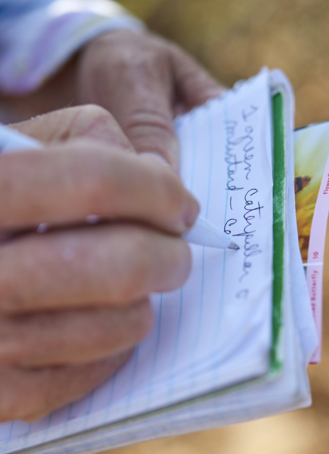 Hands depicted writing in a field journal.
