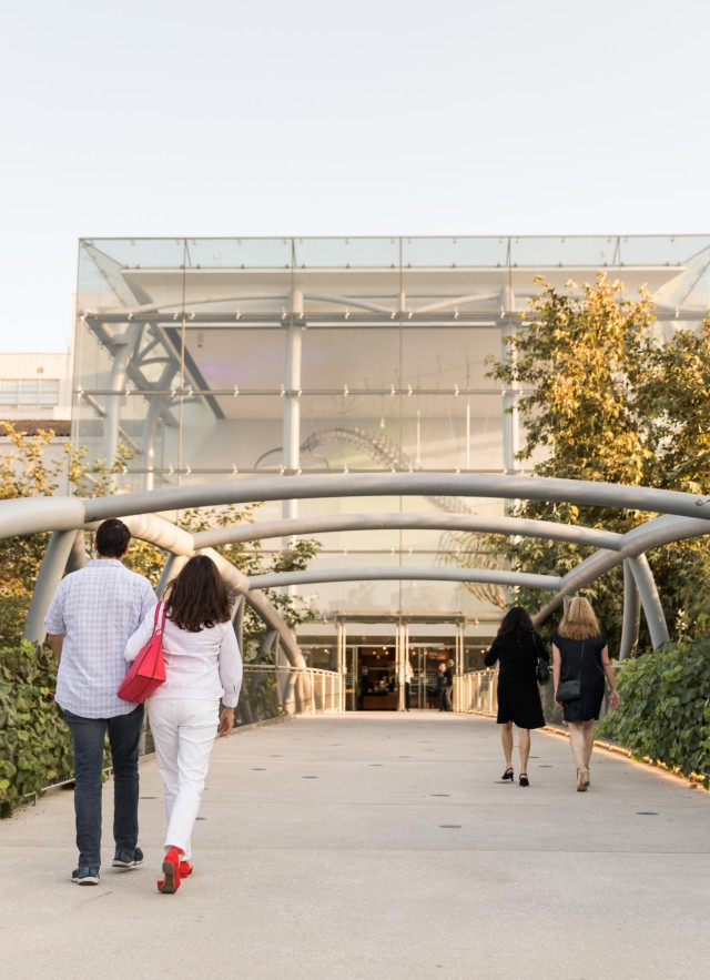 People walking across the Otis Booth Pavilion bridge