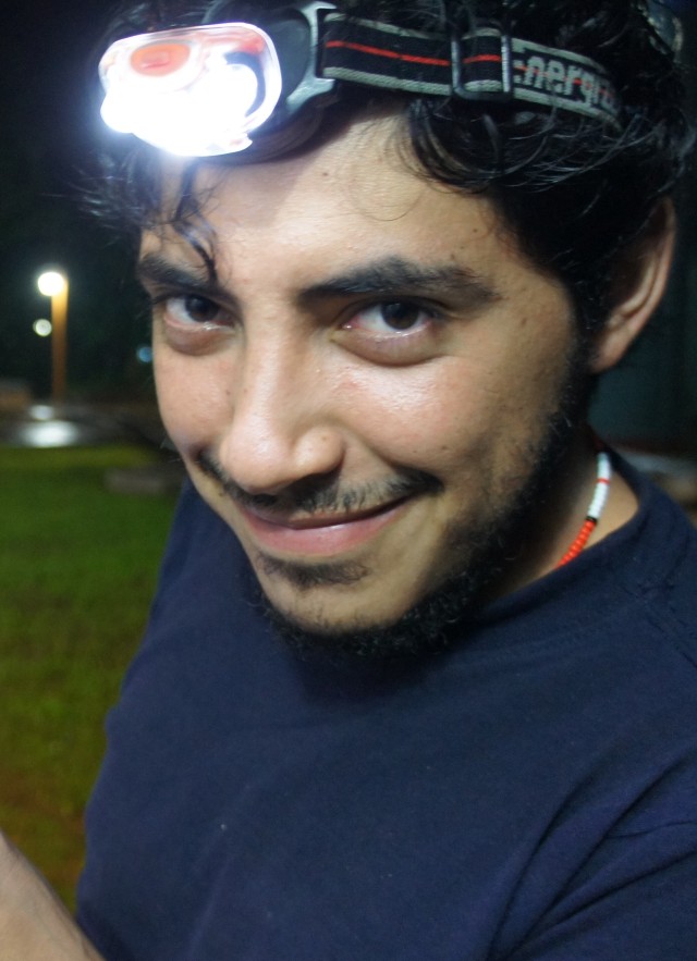 Dr. Rodrigo Monjaraz Ruedas holding specimens in a jar and wearing a head lamp at night