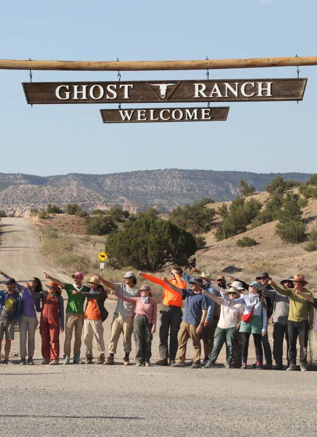 A line of people beneath a sign in the desert