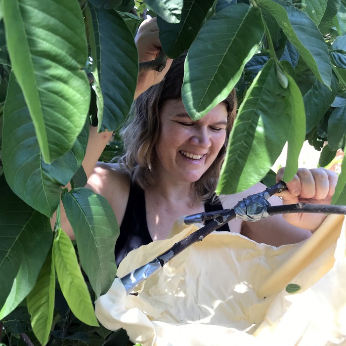 Woman holding beat sheet under a leafy bush