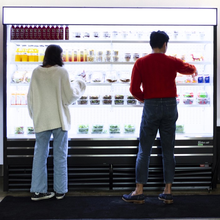 Visitors facing a glowing shelving unit with snacks