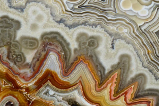 Wavy streaks of amber, orange and gray on a polished mineral surface