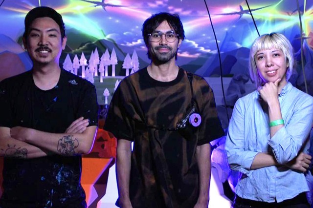 RFX1 (Jason Chang), Joel Fernando, and Yesenia Prieto in front of a glowing projected mountains, clouds, and trees in purple, blue, and green