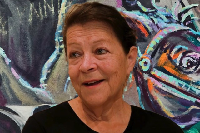 Head and shoulders portrait of Barbara Carrasco in front of colorful mural.