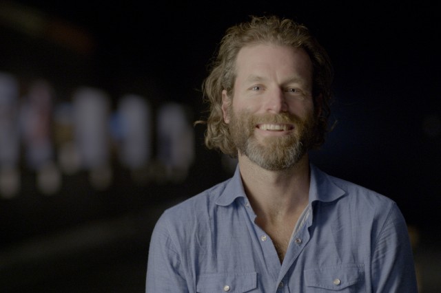 Ronan Donovan from the shoulders up, with light red hair and beard and wearing s sky blue shirt