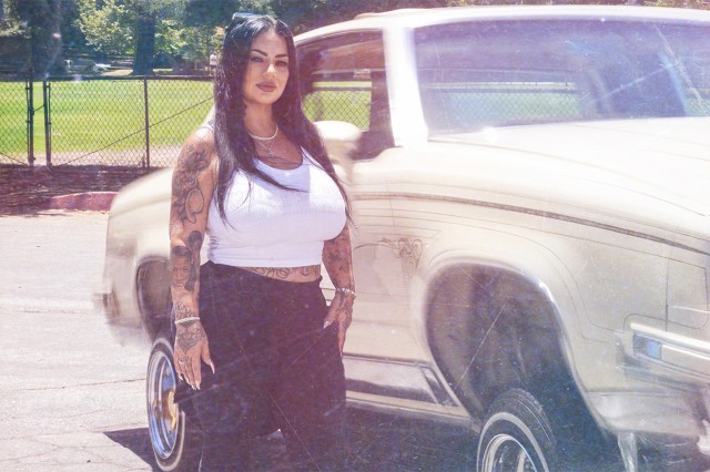 Sandy Avila standing next to a cream-colored lowrider car