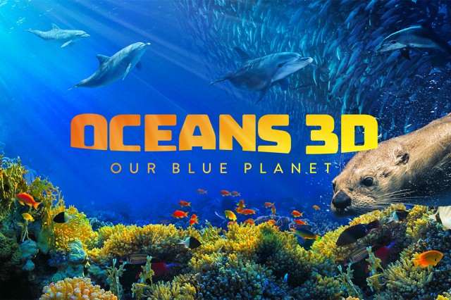 Oceans 3D: Our Blue Planet in yellow-orange capital letters over a blue ocean with dolphins swimming above a coral reef