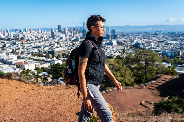 A cool-looking person wearing a backpack walks above the city skyline