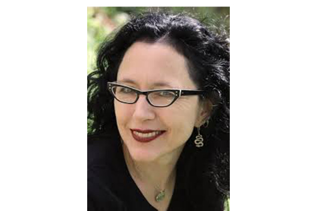 Corinna Bechko with black hair wearing cat-eye glasses and a black shirt