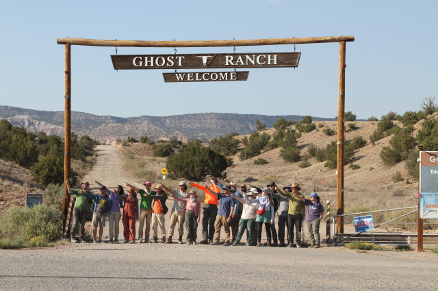A line of people beneath a sign in the desert