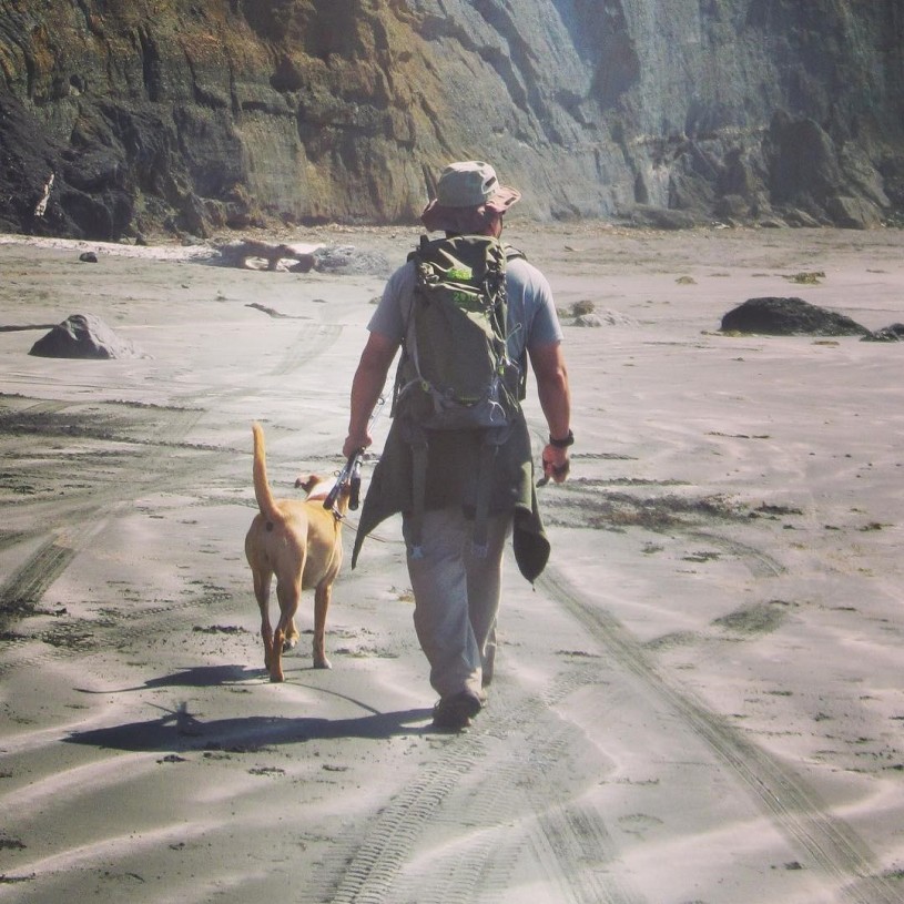 Dennis and his dog hiking on a dog-friendly beach.