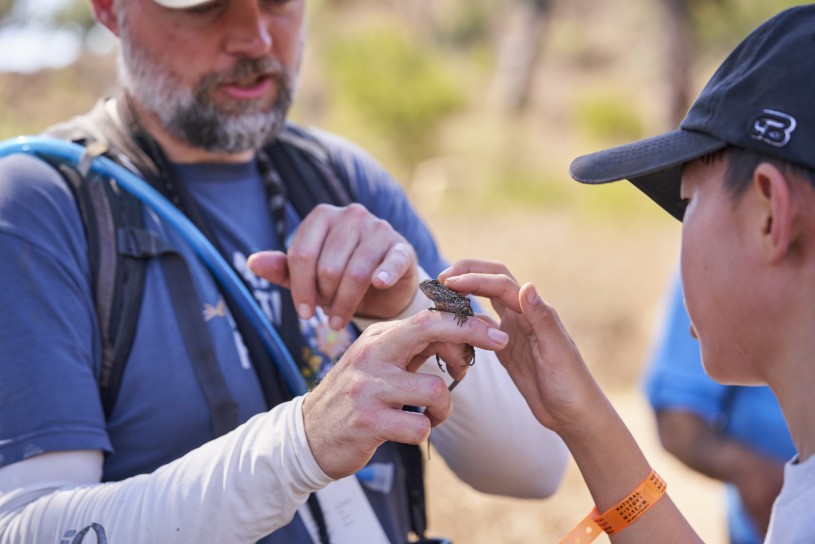 Greg Pauly introduces a lassoed lizard to hike participant 