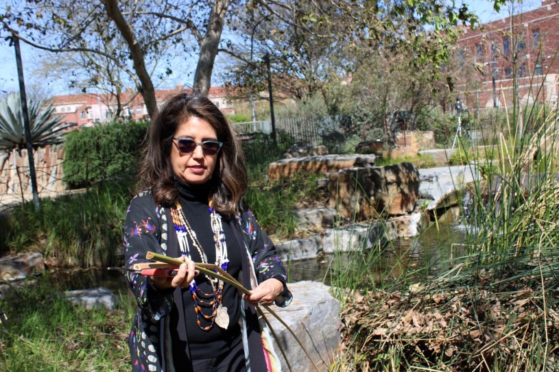 woman cuts plants next to pond 