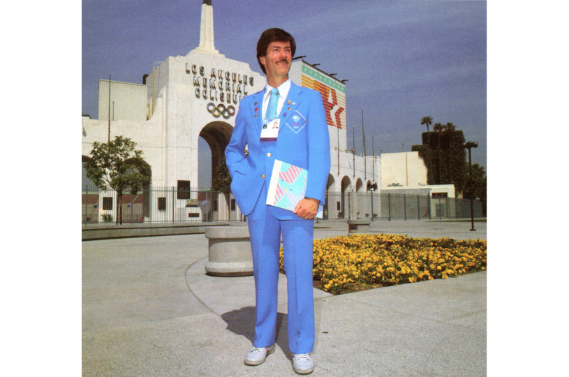 Seaver Center Collections Manager John Cahoon poses in front of the L.A. Coliseum decked out in a blue suit as volunteer for the 1984 L.A. Olympics.