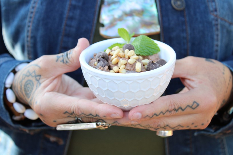 Woman with tattooed hands holding a small bowl of chocolate chia pudding