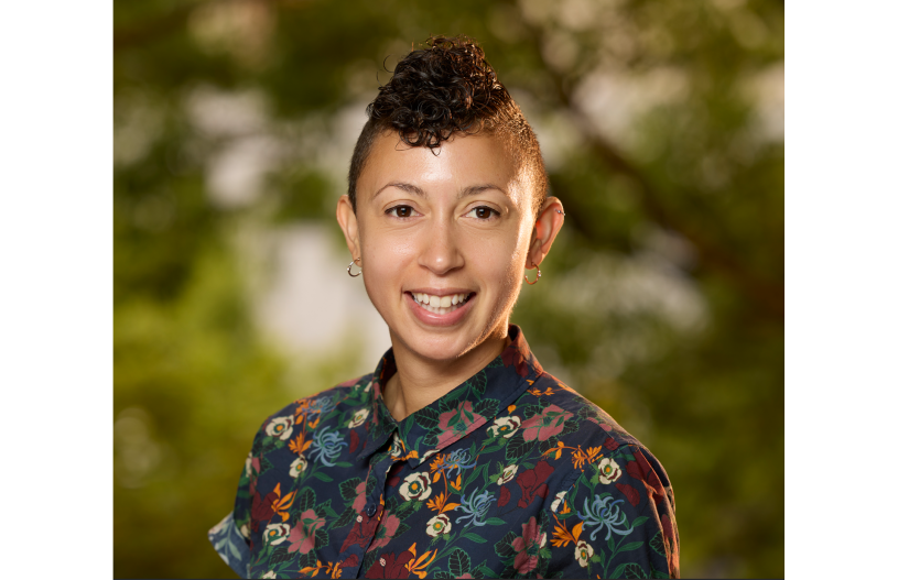 Woman with black, colorfully patterned shirt smiles at the camera