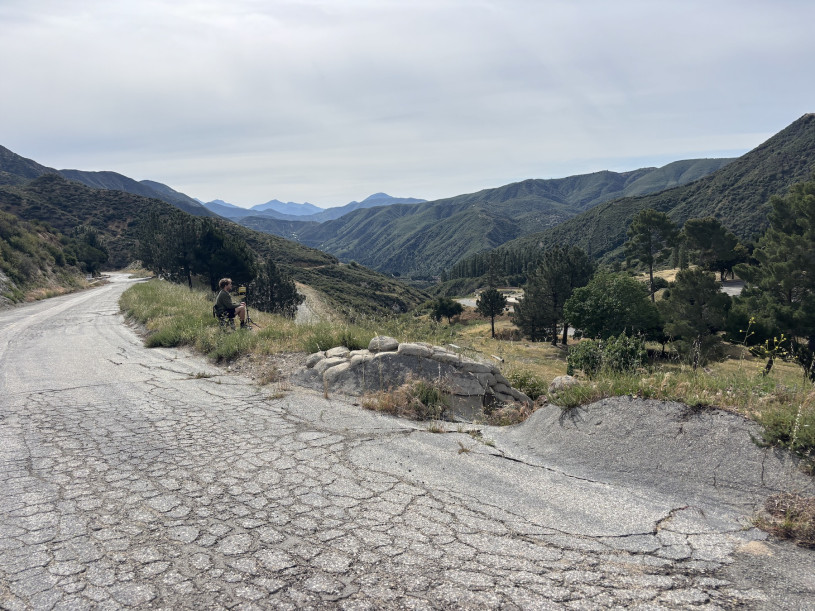 A hilly view with a road and a guy on a chair looking the other way