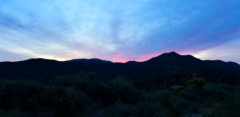 A mauve shunrise creeps over a dark hill