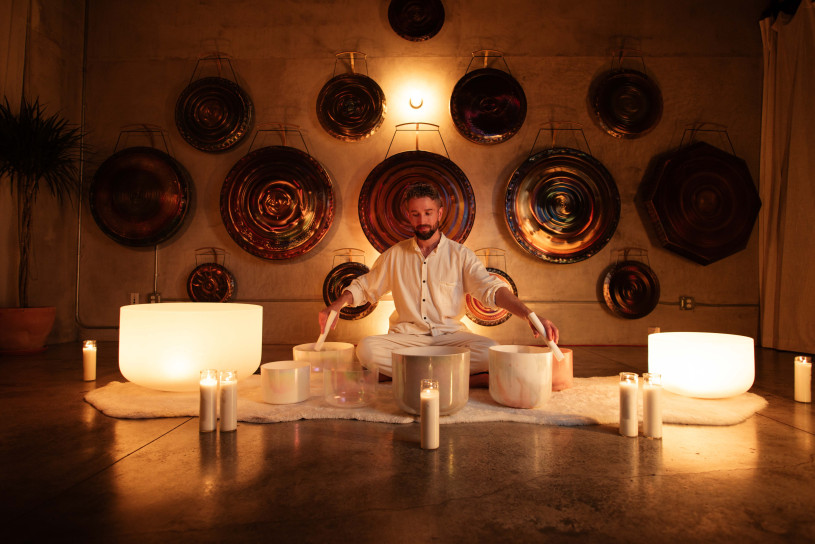 Avery Whitmore sitting crossed legged, surrounded by bowls and gongs