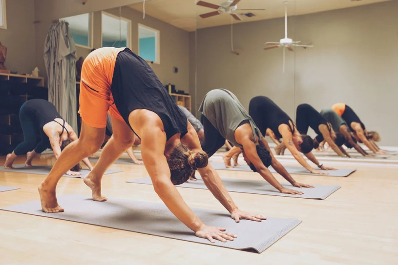 People in downward dog position on mats in a yoga class