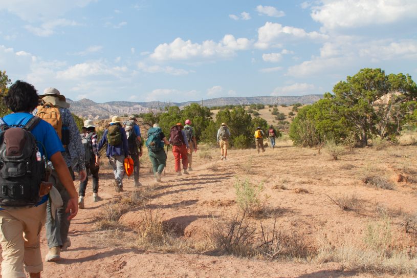 A line of folks with backpacks walking away