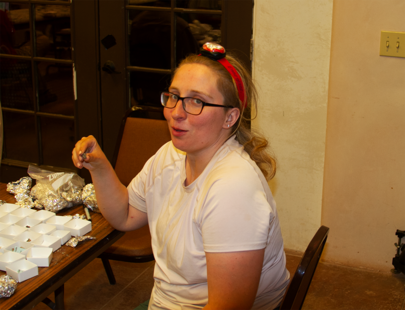 A woman in a white shirt and red headlamp holds a fossil