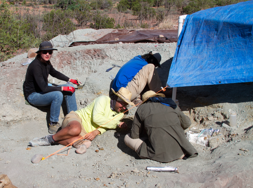 4 people by a blue tarp in the desert