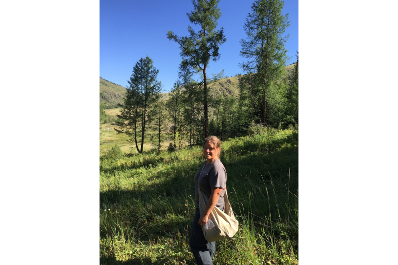 A woman walking in the grass with trees in the background