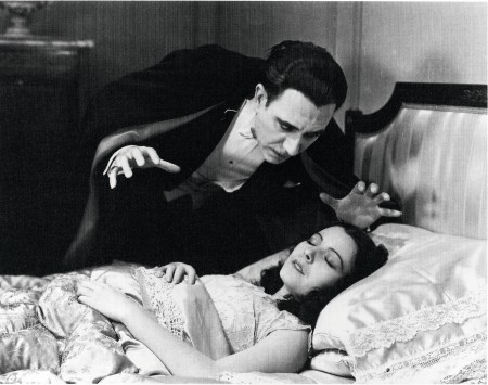 Still image from horror film Dracula. The vampire leans ominously over a sleeping woman.