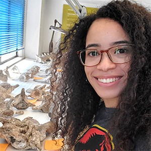 Head and shoulders portrait of Kiersten Formoso with fossils on a table 