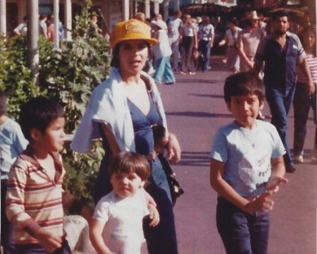 A 1980s photograph of Maricruz in a yellow cap with three young children at Disneyland.
